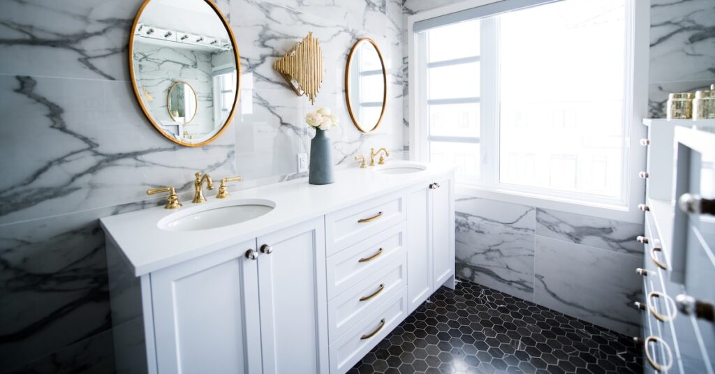 White bathroom with vanity and two mirrors.