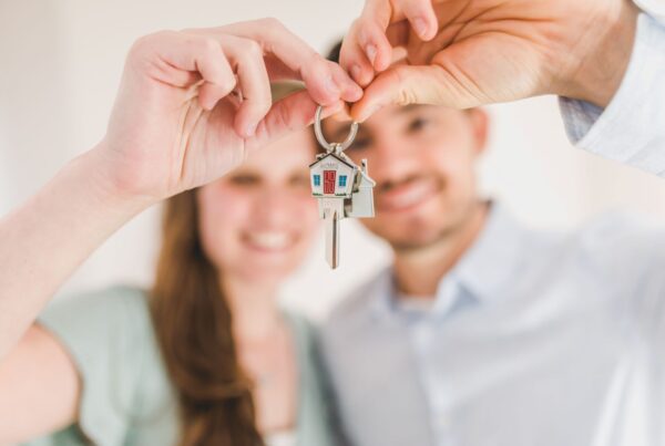 A man and a woman holding a key in the shape of a house.